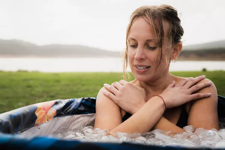 Woman experiencing cold water therapy in an inflatable portable cold plunge ice bath tub outdoors.