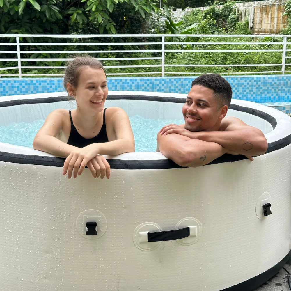 2 people relaxing in an inflatable jacuzzi set up outdoors, showing the hot tub's versatility and ease of use.